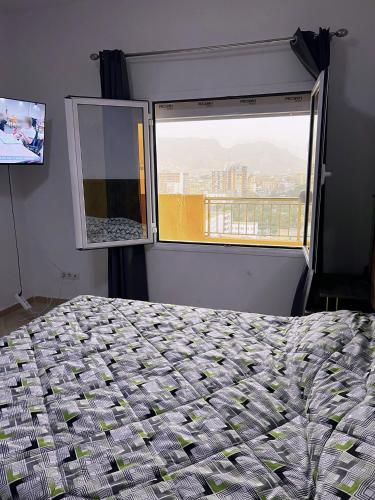 a bedroom with a bed and a window at Le balcon bleu in Oran
