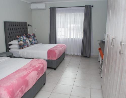 a hotel room with two beds and a window at Blooming Rose Bed and Breakfast in Polokwane