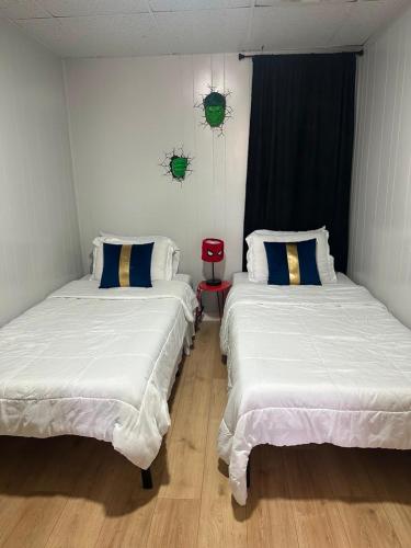 two beds in a room with white sheets at Superhero Family Home Near Downtown Amarillo in Amarillo