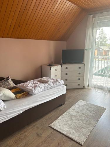 a bedroom with a bed and a dresser and a television at PEP Apartman in Balatonlelle