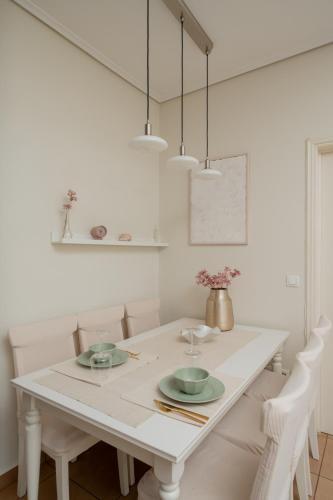 a white dining room with a white table and chairs at Naria Home by A&D Properties in Porto Rafti