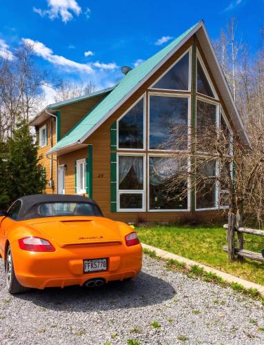 an orange car parked in front of a house at Cosy lakeside chalet in Mashteuiatsh with jacuzzi in Mashteuiatsh
