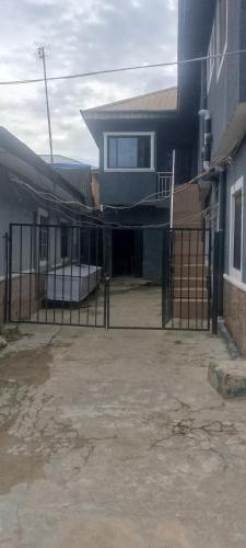 a fence in front of a building with a house at Elegance hotel in Ijaiye