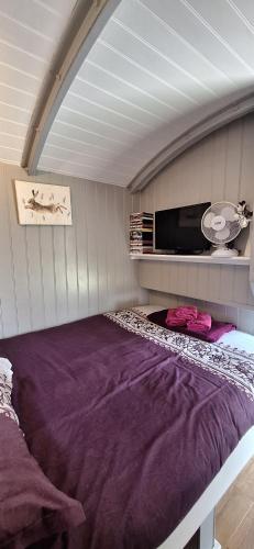 a large purple bed in a room with a ceiling at Pen-Rhos luxury glamping "Cuckoo's Nest" in Llandrindod Wells