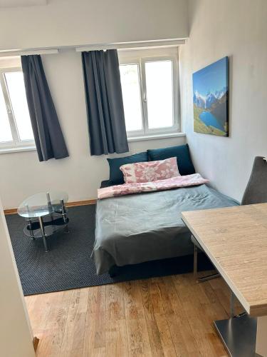 a bedroom with a bed and a table and windows at Tor zur Weinstrasse, Smart & Einfach in Leibnitz