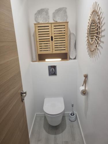 a bathroom with a toilet and a wooden cabinet at Villa cocooning in Palavas-les-Flots