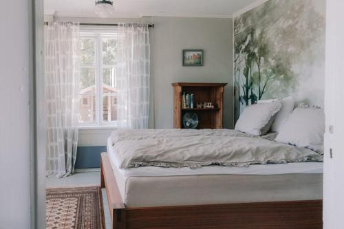 a bedroom with a large bed and a window at Cozy forest cabin with wood-fired sauna in Naantali