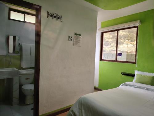 a bedroom with a bed and a toilet and a window at Green House Araque Inn in Otavalo