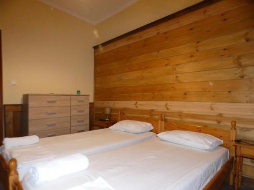 two beds in a bedroom with a wooden wall at Iona Achilleion Appartments in Achílleion