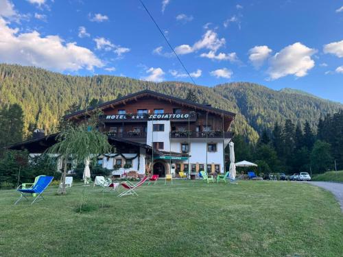 a large building with chairs in front of it at Albergo Scoiattolo Dolomites Experience in Falcade