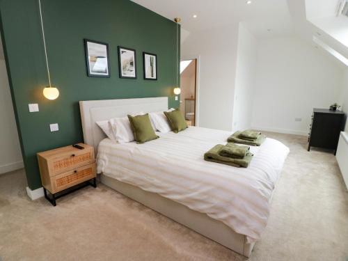 a bedroom with a large bed with a green wall at Balcarry Barn in Newton Stewart