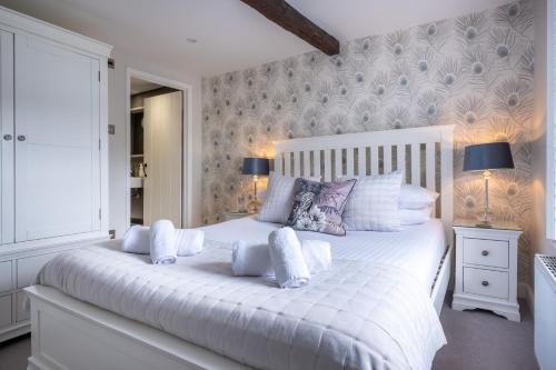 a white bedroom with a white bed with pillows at Ross Cottage in Hawkshead