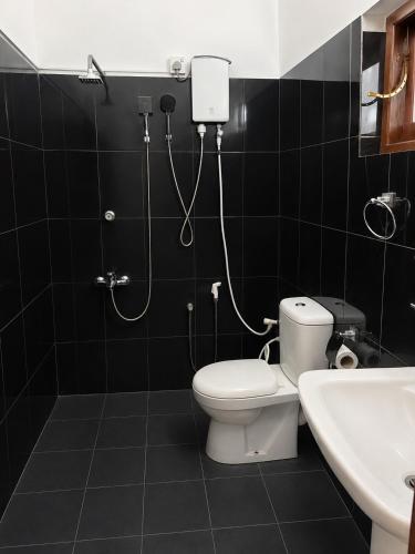 a bathroom with a white toilet and a sink at Aurelia Grand Hotel in Kitulgala