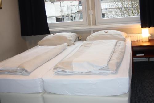 two white beds in a room with a window at Ahoi-Gästehaus in Hamburg