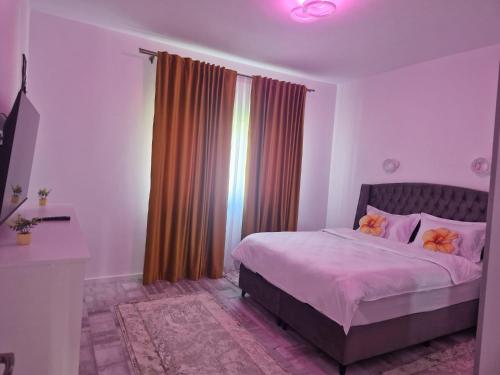 a bedroom with a bed with pink sheets and a window at Apartament 3D in Fălticeni