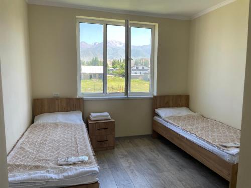 two beds in a room with a window at Moto Guest House in Kochkorka