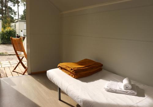 a bed with a blanket and a chair in a room at Valbom by Campigir in Sesimbra