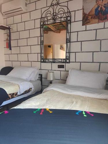 a bedroom with two beds and a mirror at Le Retour au calme Maison d'hôtes in Tinerhir
