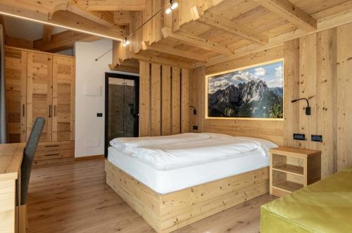 a bedroom with a bed in a wooden room at Hotel Chalet Alaska in Pozza di Fassa