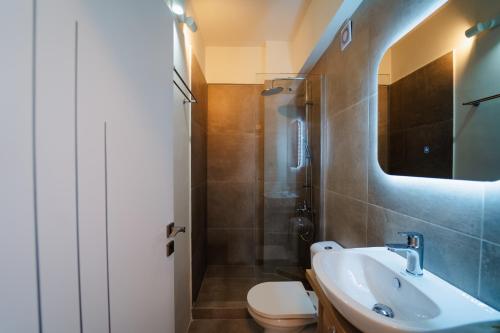 a bathroom with a sink and a toilet and a mirror at Zoe Apartment Port View Β in Rafina