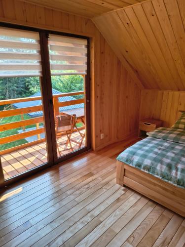 a bedroom with a bed and a balcony at Domek Góra Gbura in Ulucz