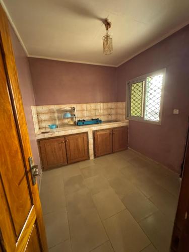 an empty kitchen with wooden cabinets and a window at Angevita City2 in Edéa