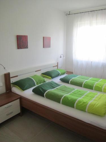 two beds in a room with green pillows on them at Ferienwohnungen Tollhof - Near Bolzano and castles, with a guest card for families and couples, offering panoramic views in Cornaiano