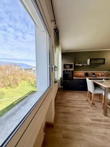 a kitchen with a large window and a table with chairs at Studio neuf parking proche centre-ville in Chambéry