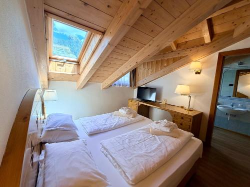 a bedroom with two beds and a window at Hotel Al Parco in Moena