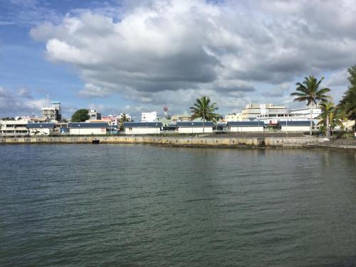 a body of water with buildings and palm trees at Orient Guesthouse Auberge in Mahébourg
