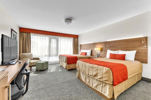 a hotel room with two beds and a flat screen tv at Motel Adam in Gatineau