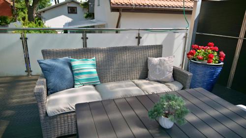 a wicker couch on a patio with a table and flowers at Nadmorska Miła in Gdańsk