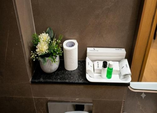 a bathroom counter with toilet paper and a vase with flowers at EMBASSY PARK - Near US consulate, Apollo hospital, Sankaranethralaya in Chennai