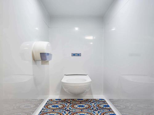a white bathroom with a toilet and a rug at hotelF1 Avignon Nord in Sorgues