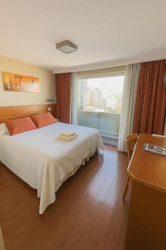 a hotel room with a bed and a large window at Hotel Benevento in La Plata