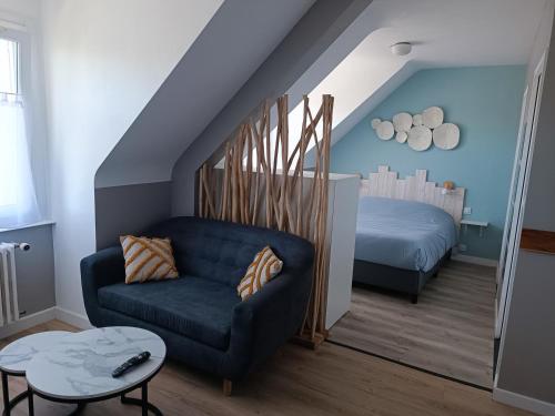 a living room with a blue couch and a bed at Hôtel-Relais De Trefeuntec in Plonévez-Porzay