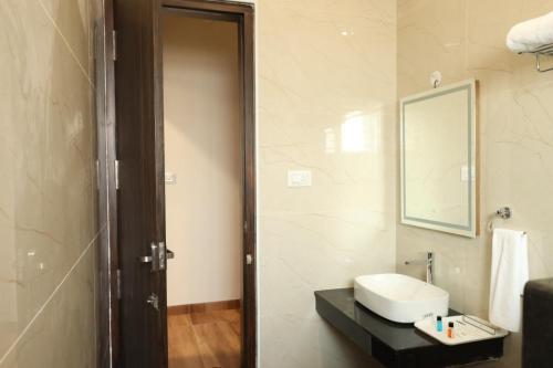 a bathroom with a sink and a mirror at Skvr Grand in Theni