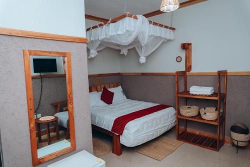 a small bedroom with a bed and a mirror at Arusha Giraffe Lodge in Arusha