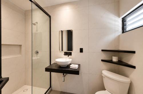 a bathroom with a toilet and a sink and a shower at Aruma Suites in Playa del Carmen