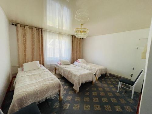 a hotel room with two beds and a chandelier at Azem Guest House in Kasymbek
