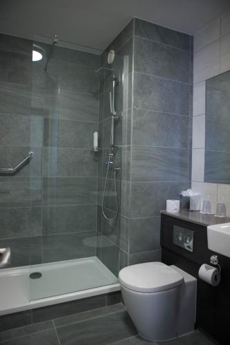 a bathroom with a shower and a toilet and a sink at Maldron Hotel Sandy Road Galway in Galway