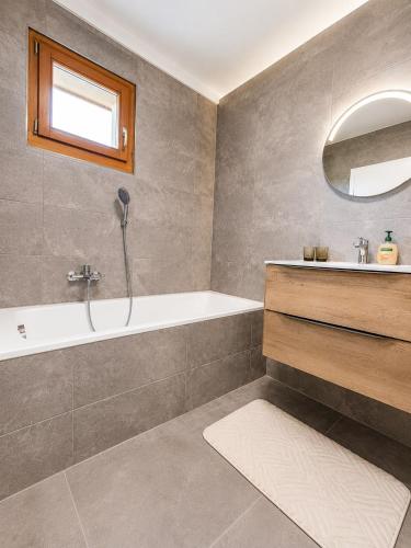 a bathroom with a bath tub and a sink at La maison IDEL in Yvonand