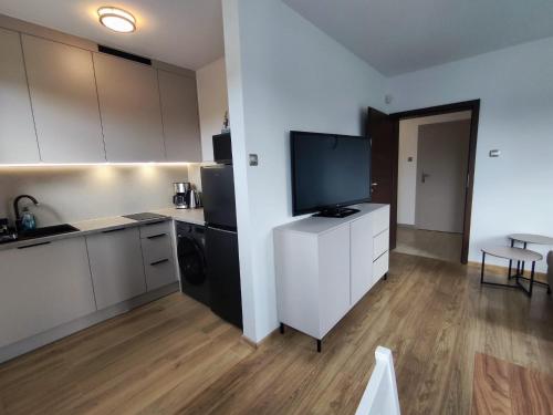 a kitchen with a flat screen tv on a white cabinet at Willa Hydrograf - rowery i parking bezpłatnie in Ustka