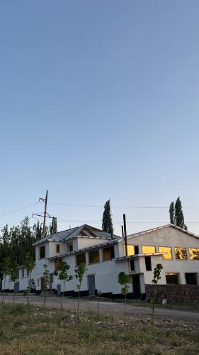 a large white building with trees in front of it at Gostevoy dom Dovul in Chimgan