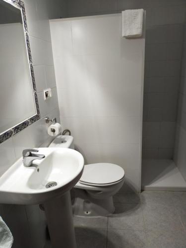 a white bathroom with a toilet and a sink at Hostal El Polígono in Lucena