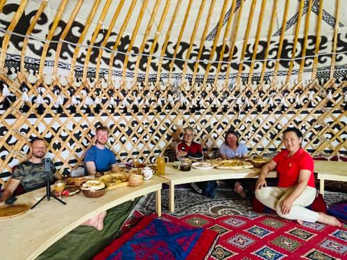 a group of people sitting around a table in a room at Azem Guest House in Kasymbek