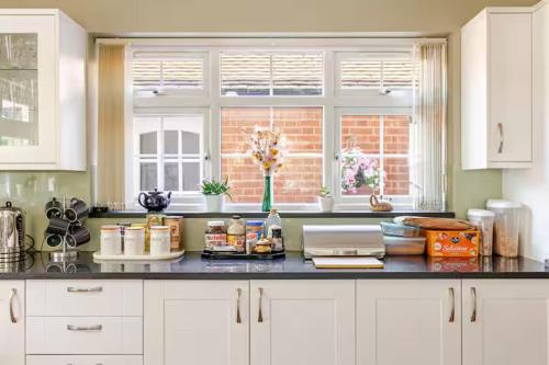 a kitchen with white cabinets and a black counter top at Leafy Suburban Bed and Breakfast in Northwood