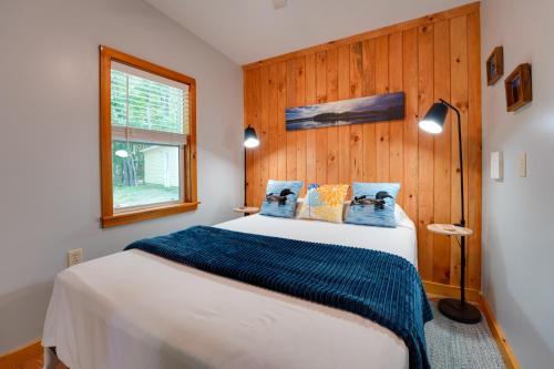 a bedroom with a large bed with a wooden wall at Private Dock & Deck: Tranquil Dam Pond Cottage! in Augusta