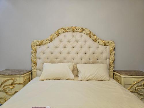 a large bed with a large headboard and two tables at مزرعه فلج فارم Falaj-farm in Falaj al Mu‘allá