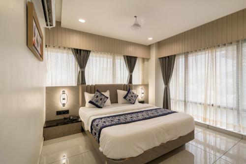 a bedroom with a large bed with windows at Hotel Lavish Regency in Ahmedabad